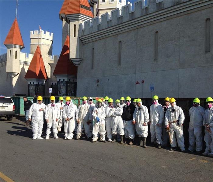 several employees dressed in PPE in front of a stone building