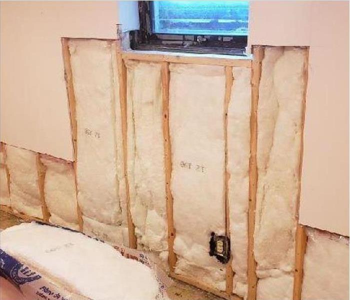 exposed wall, showing studs and new insulation below a window