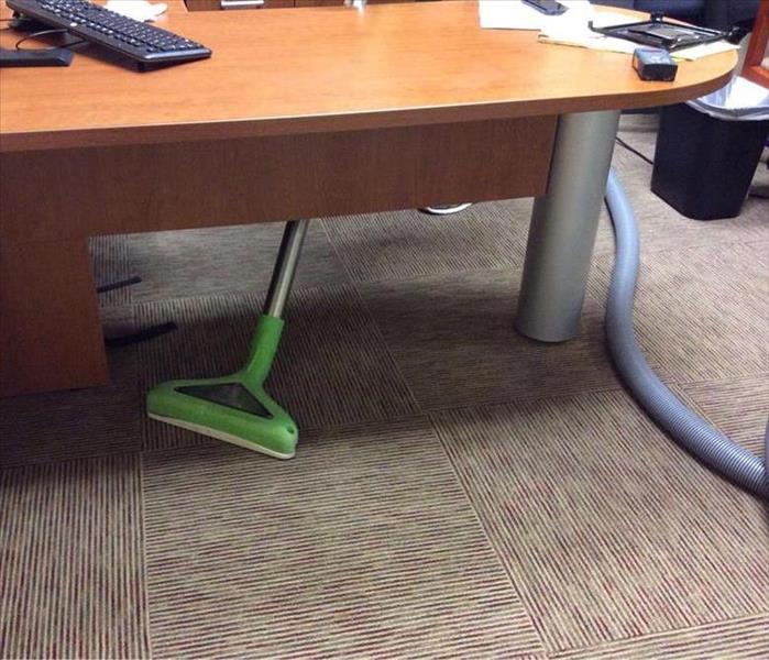 office with brown carpet and a wood desk, and a wand scrubbing the floor