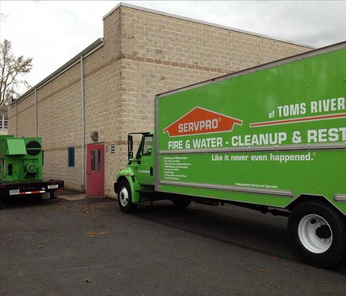 Green SERVPRO Truck in a parking lot of a school